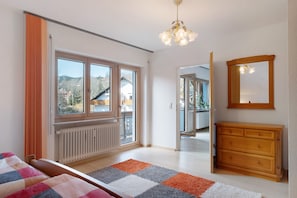 Un dormitorio con cama, cómoda, espejo y vistas al exterior.