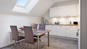 A modern kitchen with a skylight, white cabinets, and a dining area with a table and chairs. - Apartment 'Kessler Waldblick' with Balcony and Wi-Fi (Häusern)