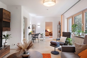 Una sala de estar moderna con sofá, sillón y zona de comedor.