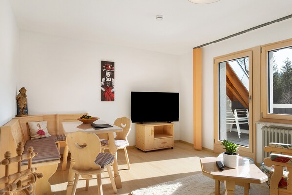 A modern living room with a TV, wooden furniture, a window, and a plant.