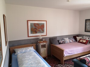 A bedroom with two beds, a bedside table with a lamp, a framed picture on the wall, and a patterned rug.