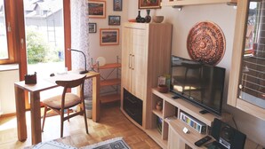 A living room with a television, wooden furniture, a cabinet, and various wall decorations.