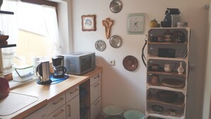 A kitchen with a microwave, coffee maker, and shelves with dishes.