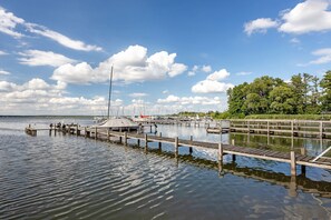 En rolig sø med en træbrygge, der strækker sig ud i vandet, omgivet af træer og en klar himmel.