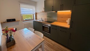 Eine kleine Küche mit Holztischplatte, integriertem Backofen und dunklen Schränken.