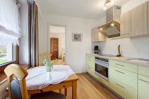 Une cuisine équipée d’une table à manger, de chaises, d’une cuisinière et de placards.