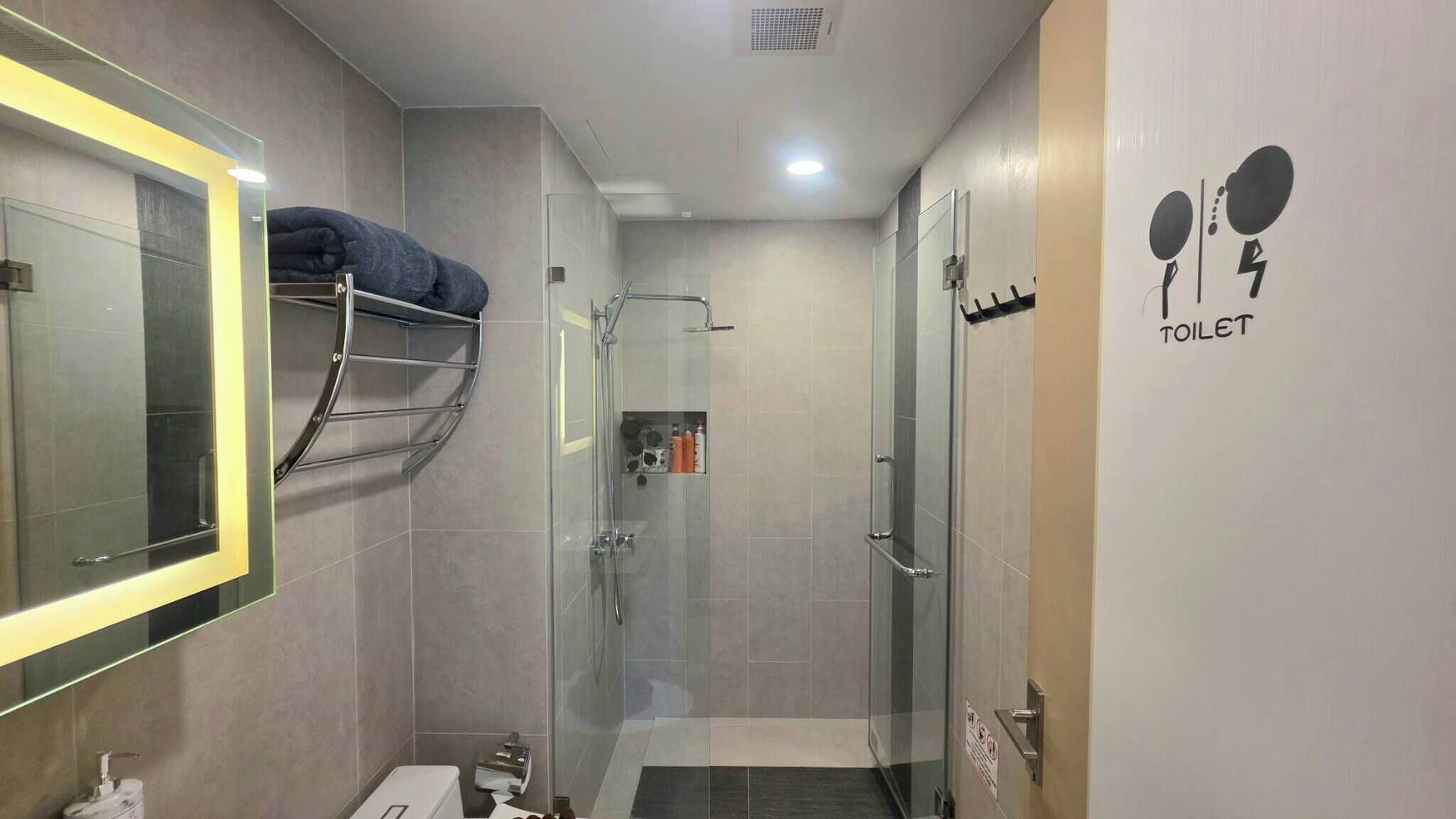 Ein modernes Badezimmer mit Duschkabine aus Glas, Handtuchhalter, Toilette und Waschbecken.