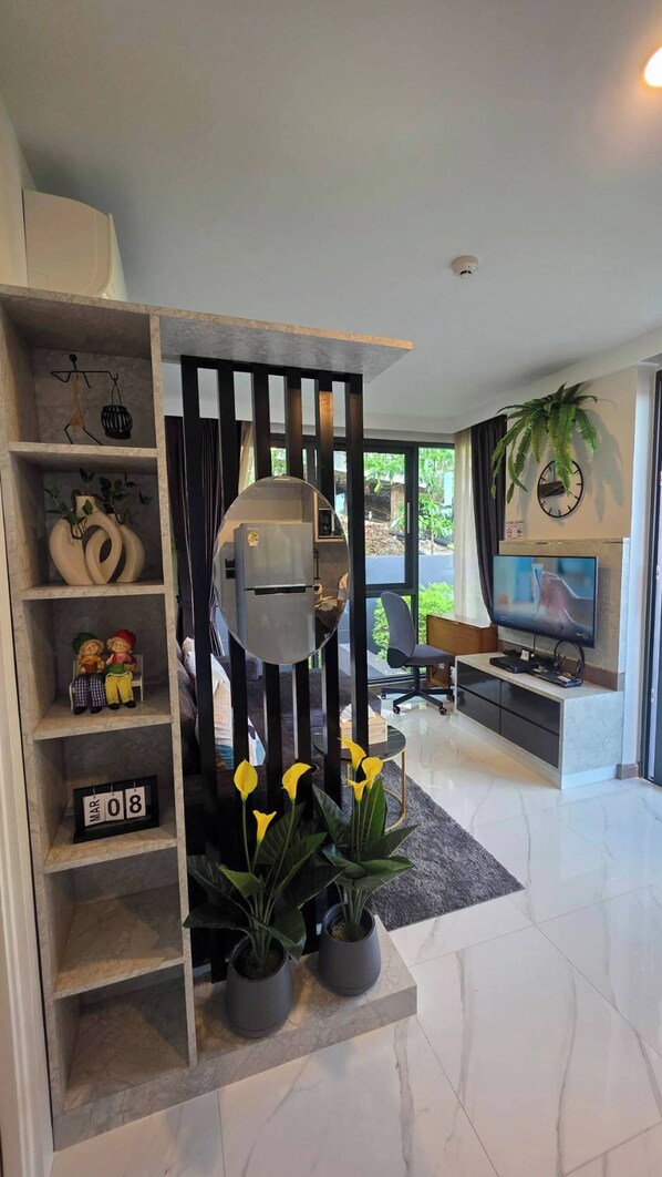 A modern living room with a built-in grill, a TV, and a potted plant. - Room-a301- 1 Bedroom Corner Condo Forest (Krabi)