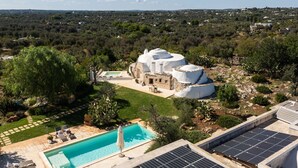Een moderne villa met een zwembad, zonnepanelen en uitzicht op het omliggende landschap.