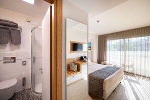 Habitación de hotel con ducha, inodoro, cama y vistas al exterior.