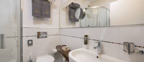 A modern bathroom with a glass shower enclosure, a white sink with a chrome faucet, and a toilet.