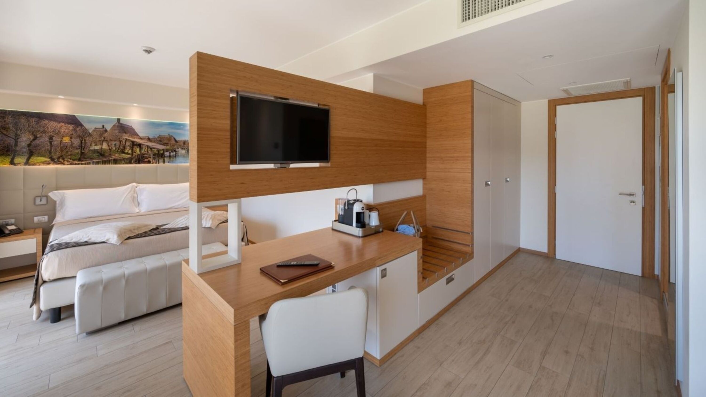 Una habitación de hotel moderna con cama, escritorio, televisor y armario.