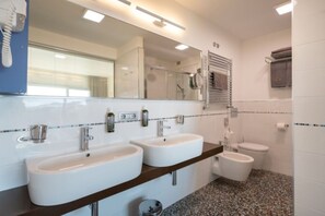 A bathroom with two sinks, a toilet, and a shower.