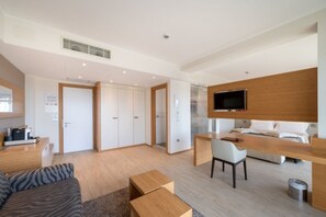 Moderni hotellihuone, jossa on sänky, työpöytä, tuoli ja televisio.
