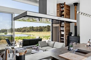 Un salon moderne doté d’un grand mur de verre, d’un canapé, d’une table basse et d’une cheminée.