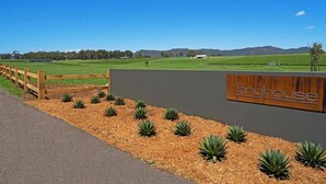 A sign for "The Longhouse" with a view of a rural landscape and a wooden fence.