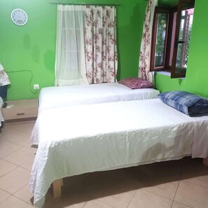 Quarto com duas camas, um relógio na parede e uma janela com cortinas.