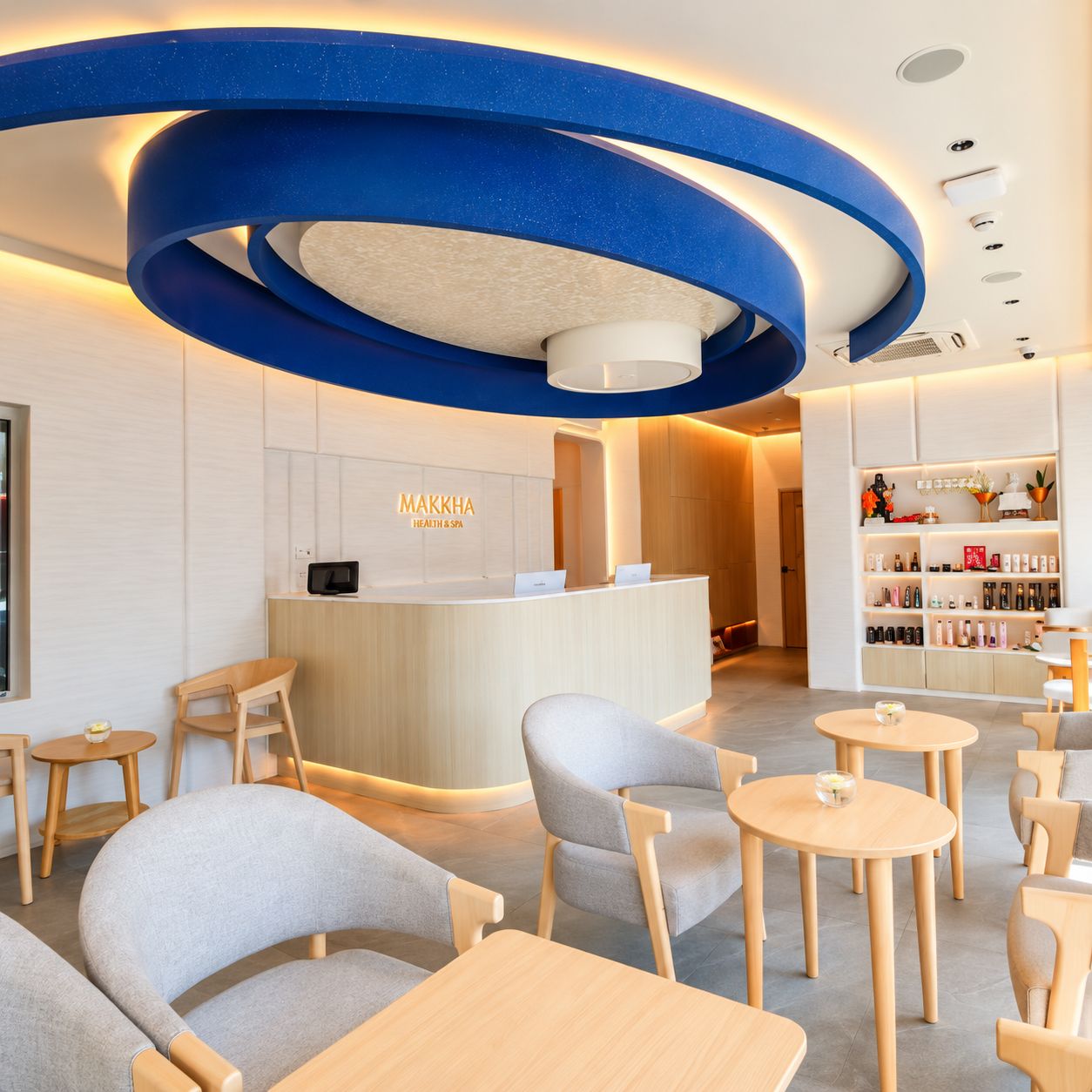 Een moderne receptie met een gebogen blauw plafond, een receptiebalie en zitgedeeltes.