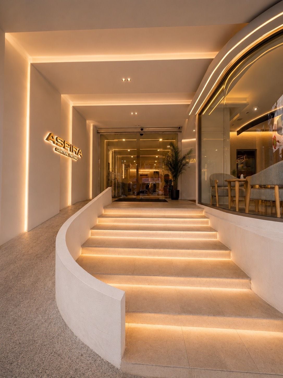 Ein modernes Hotelinnere mit einer geschwungenen Treppe, einer Rezeption und einer Sitzecke mit Blick.