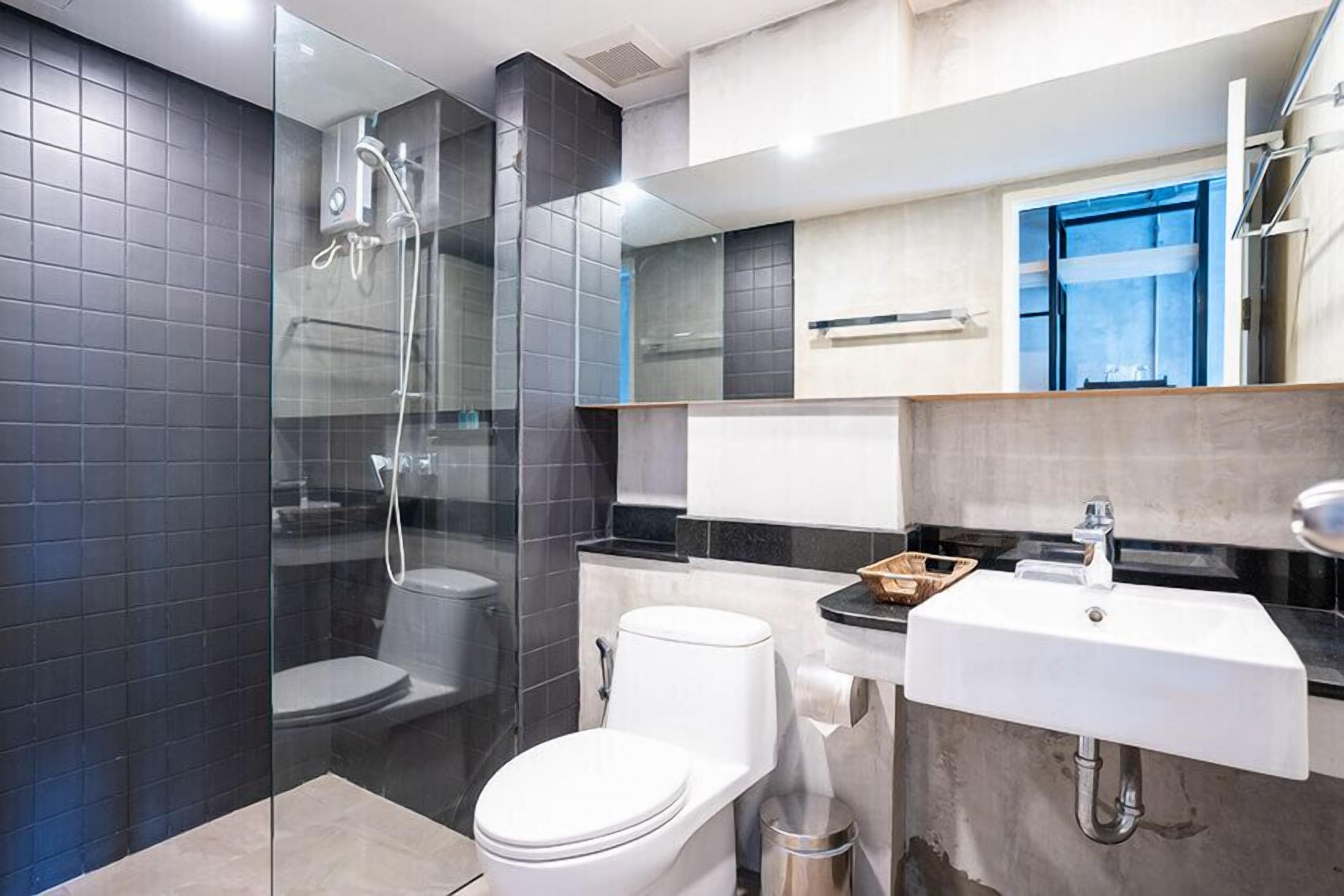 Une salle de bain moderne avec une douche à parois de verre, des toilettes blanches et un lavabo avec un miroir au-dessus.