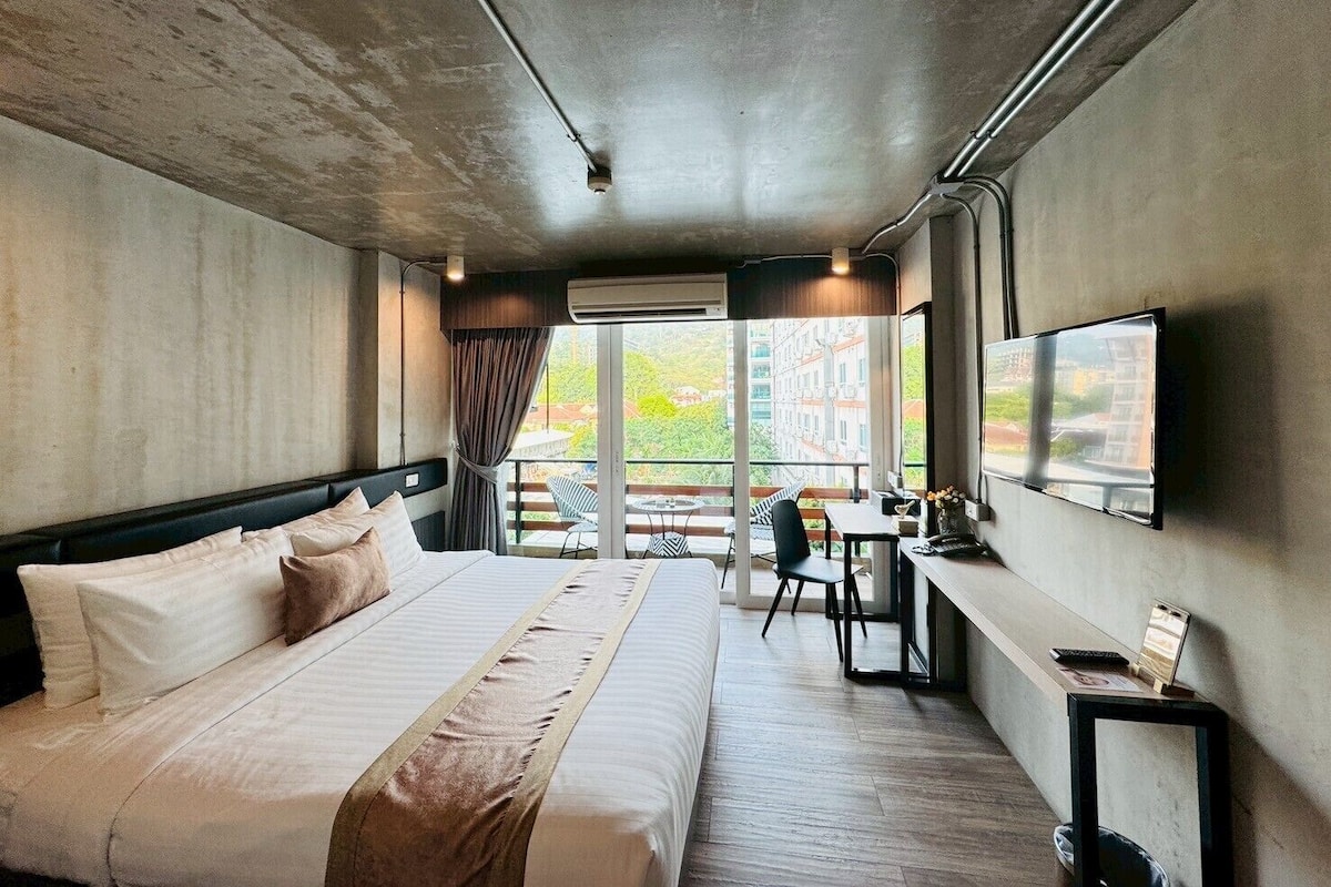 Una habitación de hotel moderna con una cama grande, un escritorio y un televisor.