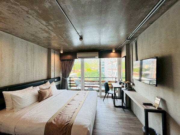 Une chambre d’hôtel moderne, dotée d’un grand lit, d’un bureau et d’une télévision.