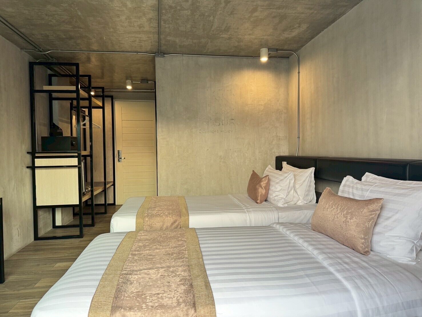 A modern hotel room with two beds, a desk, and a wardrobe.