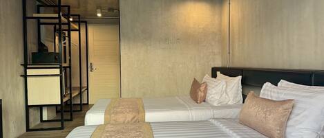 A modern hotel room with two beds, a desk, and a wardrobe.