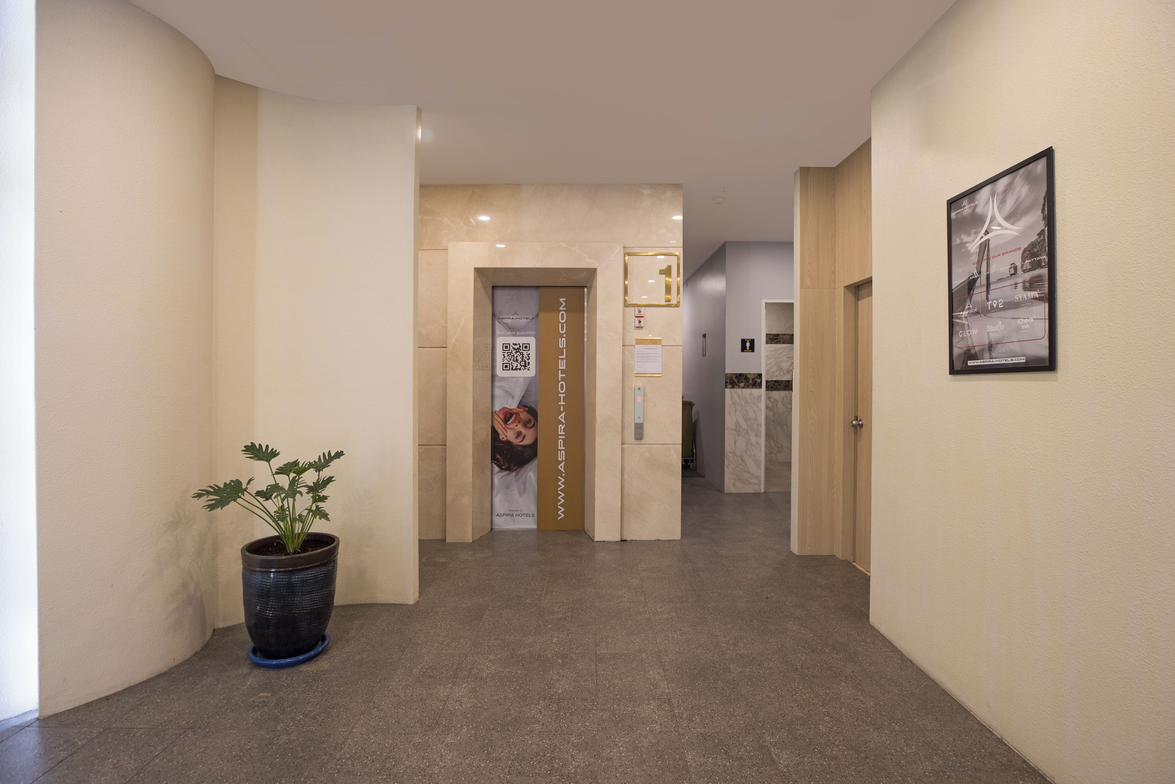Un pasillo de hotel con una planta en maceta, un letrero que indica la habitación 1 y un cuadro en la pared.