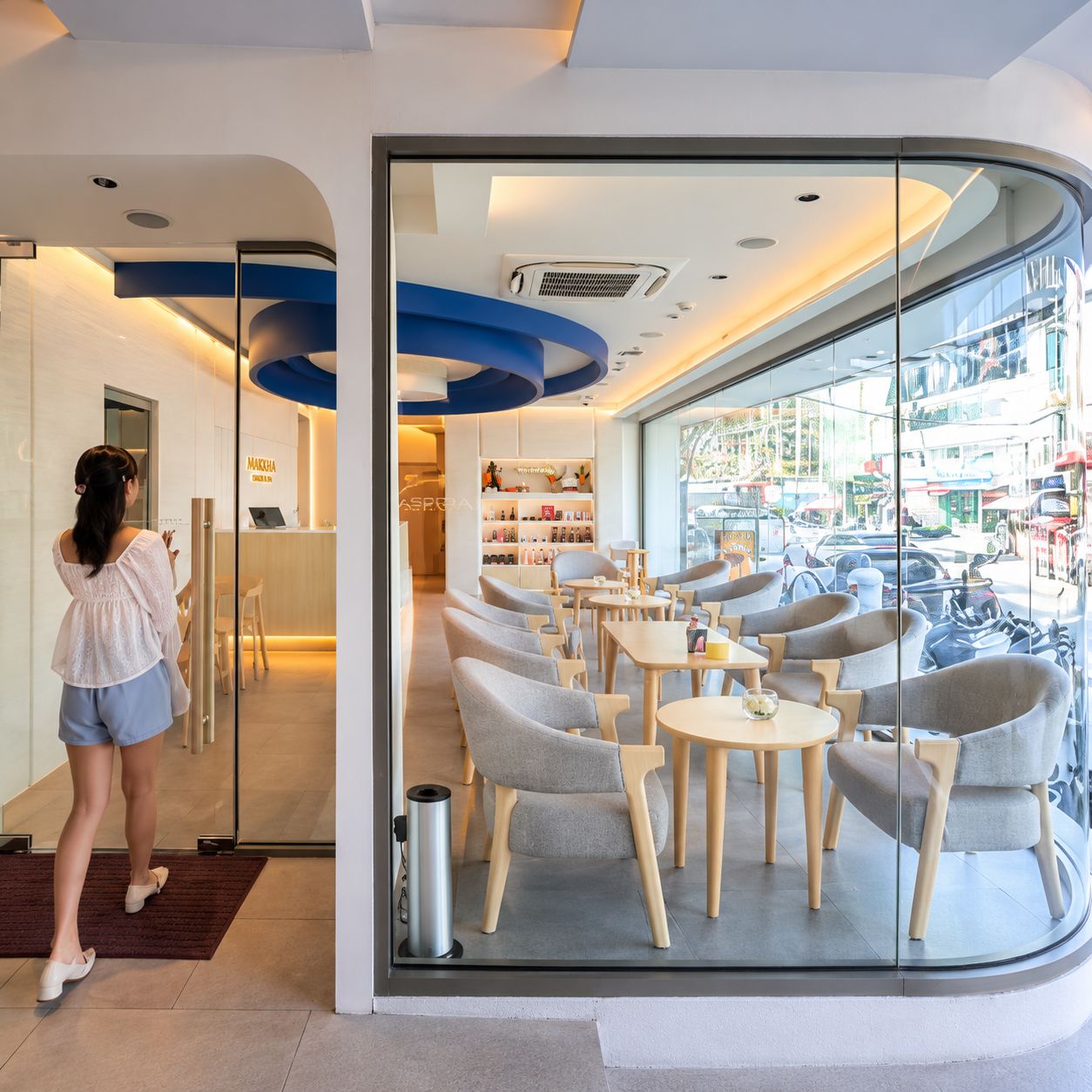 Un interior moderno con una mesa de recepción, zona de estar y vista a la calle.