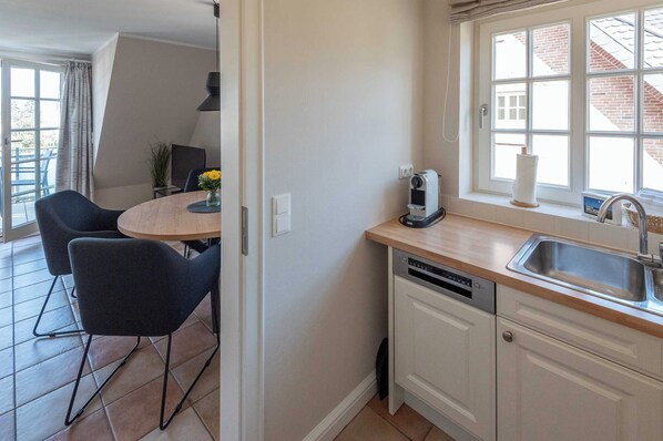 Cocina compacta con lavaplatos, pileta y ventana con vista a un edificio de ladrillo.