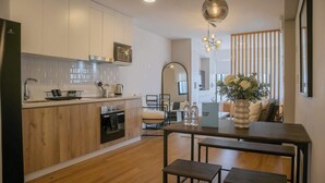 A modern kitchen with wooden cabinets, a built-in oven, and a dining area with a wooden table and bench. - w* | Modern 1BR in San Isidro (Lima)