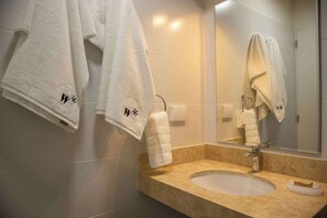 Une salle de bain avec un lavabo, un miroir et des serviettes accrochées au mur.