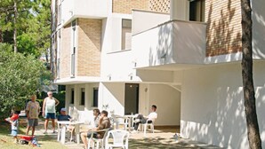 Un patio con mobiliario exterior, una zona cubierta y un edificio de fachada de ladrillo.