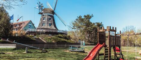 A windmill, a playground with a slide, and a building with flags.