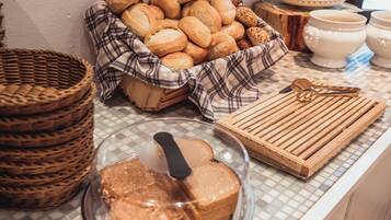 Eine Küchenarbeitsplatte mit einem Brotkorb, einem Holzschneidebrett und einem Glasbehälter mit Kuchen.