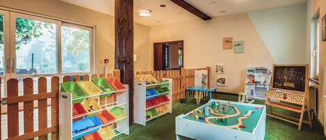 A children's playroom with a foosball table, storage bins, and educational toys.