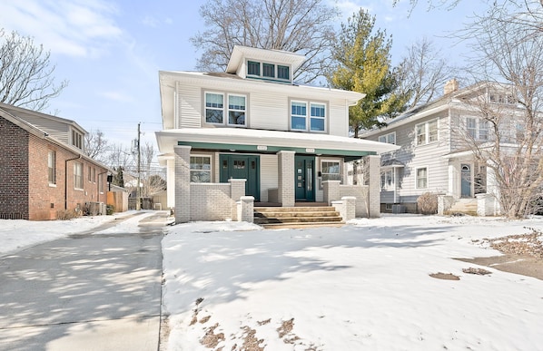 A two-story house with a front porch and a garage. - Adorable Broad Ripple Duplex! (Indianapolis)