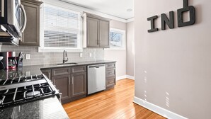 Une cuisine moderne avec des meubles gris, une cuisinière en acier inoxydable et un lave-vaisselle.