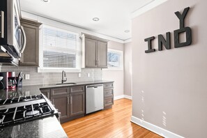 A modern kitchen with grey cabinets, a stainless steel stove, and a dishwasher. - Adorable Broad Ripple Duplex! (Indianapolis)