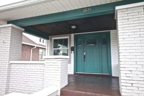 A house with a green door, white brick walls, and a number 5152 on the roof.