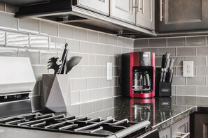 Een keuken met een moderne kookplaat, een koffiezetapparaat en een messenblok op het aanrecht.