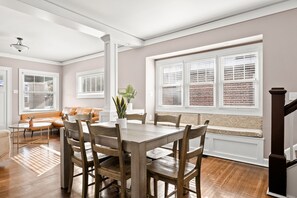 A dining area with a wooden table and chairs, a bench, and a potted plant. - Adorable Broad Ripple Duplex! (Indianapolis)