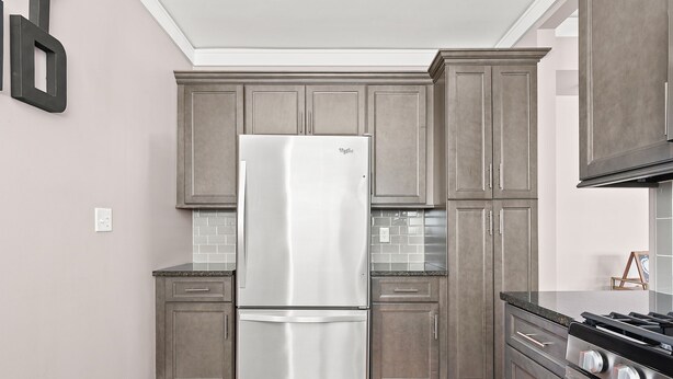 A kitchen with grey cabinets, a stainless steel refrigerator, a tiled backsplash, and a gas stove. - Adorable Broad Ripple Duplex! (Indianapolis)