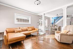 A modern living room with a leather sofa, a glass coffee table, and a beige armchair.