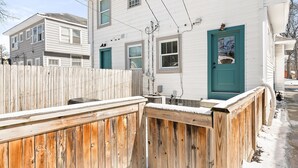 A two-story house with a wooden fence and a blue door. - Adorable Broad Ripple Duplex! (Indianapolis)