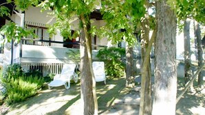 A courtyard with trees, a white building, and two white lounge chairs.