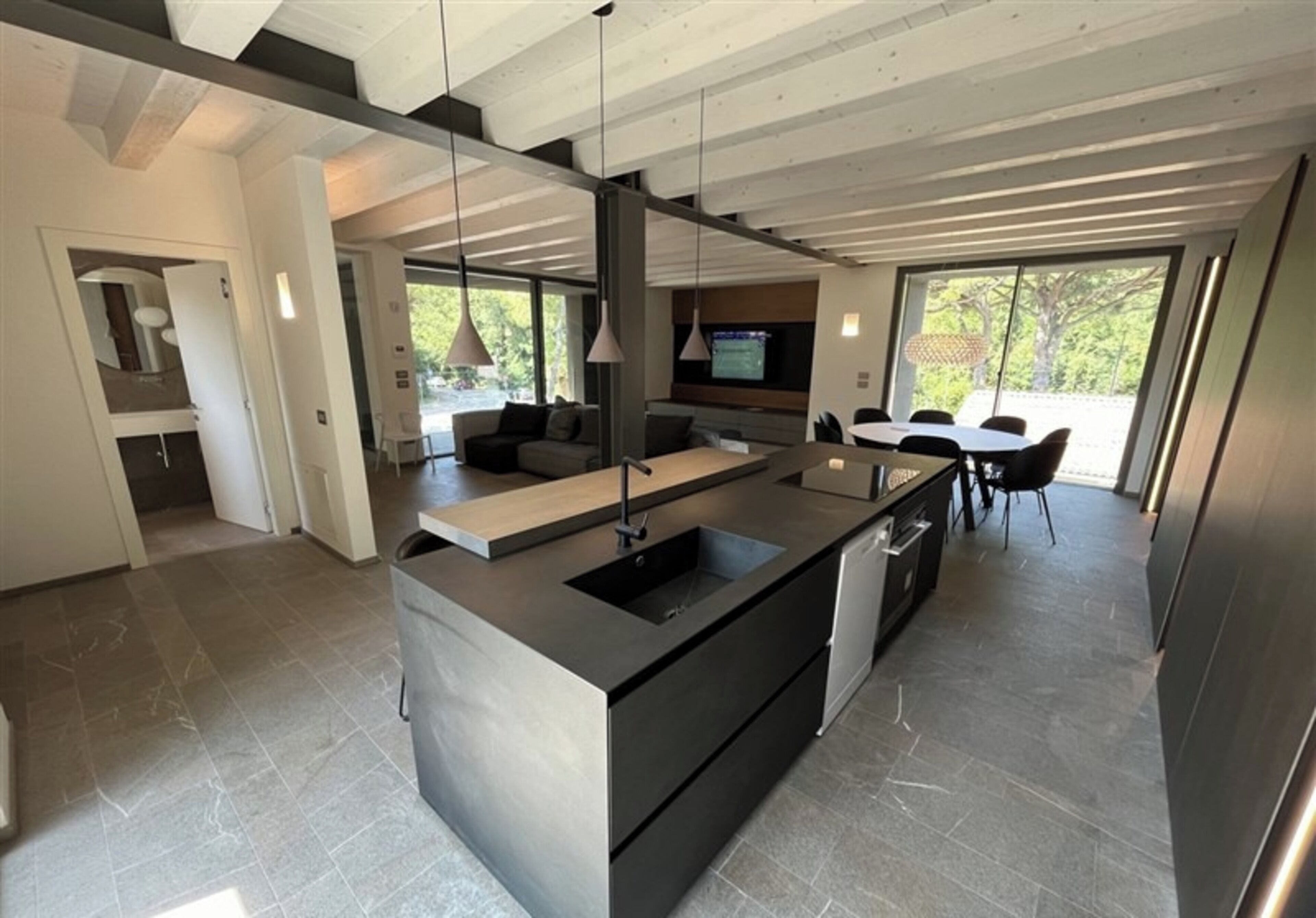 A modern kitchen with a large island, built-in appliances, and a dining area with a table and chairs.