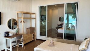Habitació d'hotel amb escriptori, dos llits, un armari, un mirall i una gran porta corredissa de vidre a un balcó.