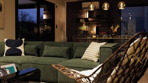 Una sala de estar moderna con un sofá verde, una silla de mimbre y un comedor con una mesa y sillas.